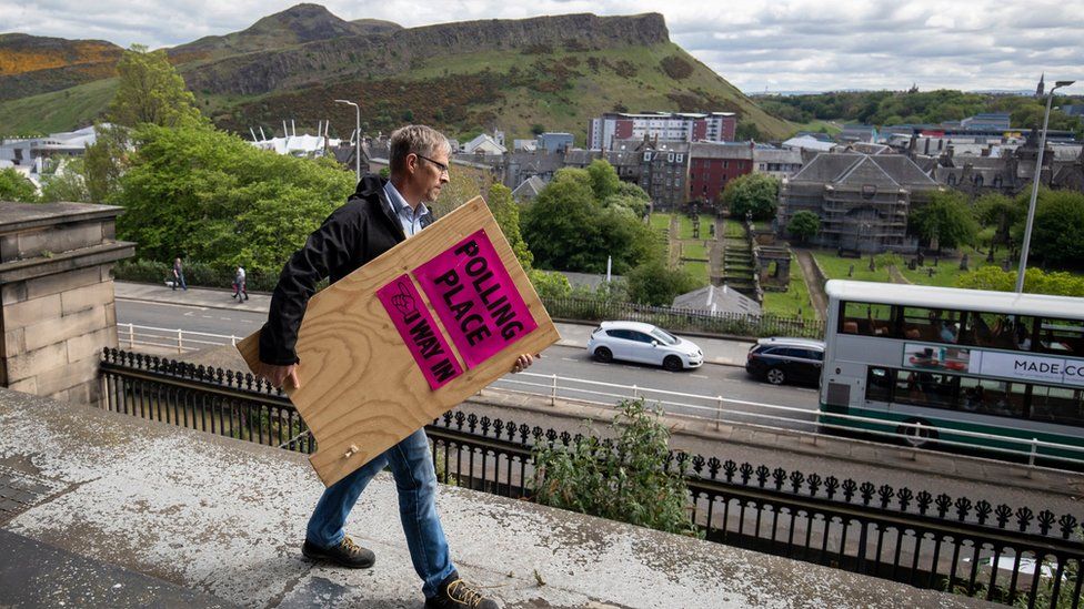 Election staff member carries a polling station sign in Edinburgh