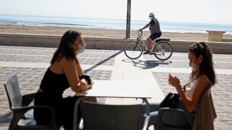 Women wearing protective masks sit on a terrace of a restaurant at Malvarrosa beach, as some Spanish provinces are allowed to ease lockdown restrictions during phase one, amid the coronavirus disease (COVID-19) outbreak, in Valencia, Spain May 18,