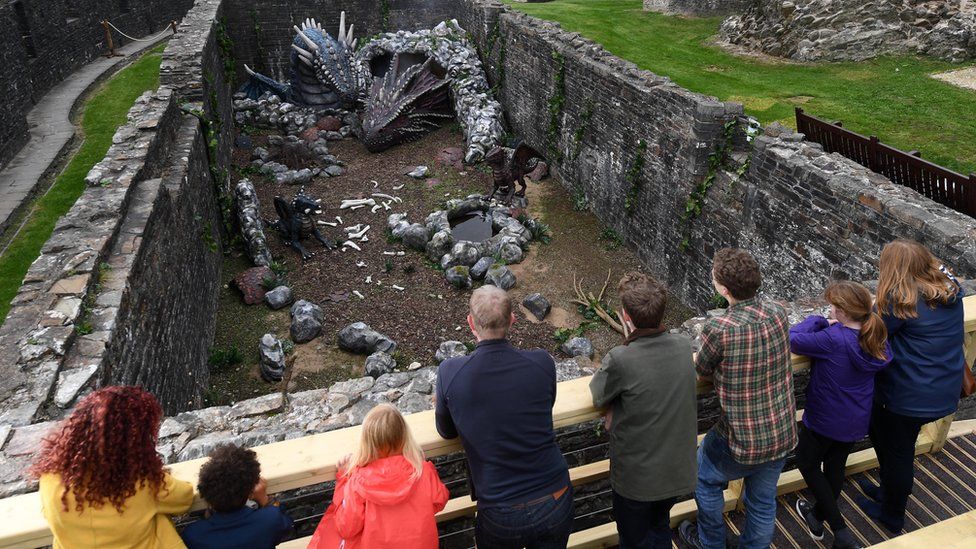 A group of people looking at the model dragons at Caerphilly Castle
