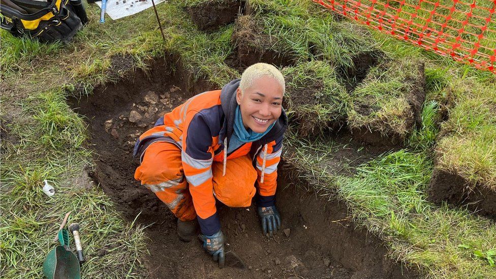 Smiling archaeologist digging trench