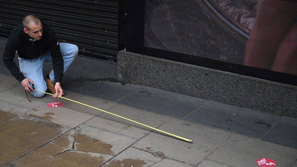 A two metre social distancing sign is measured on Oxford Street in London,
