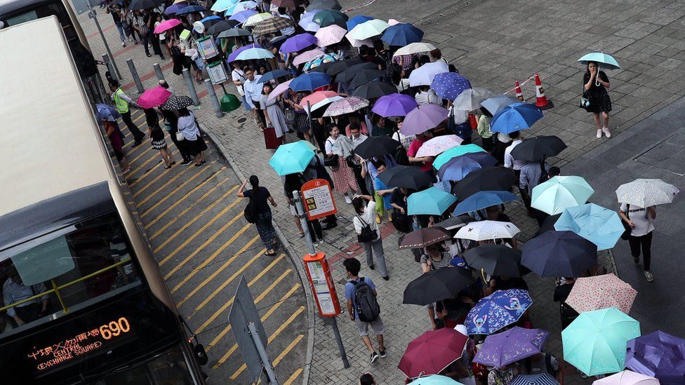 Stranded passengers queue for a shuttle bus