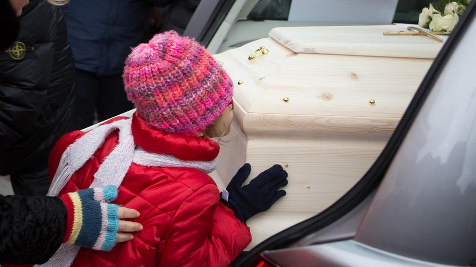 One of four children of Eleonora Girolimini kisses the coffin of her mother after the funeral Mass at the Senigallia Cathedral in Ancona, central Italy, 15 December 2018