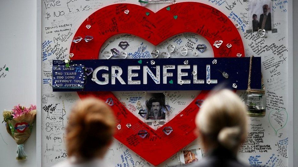 Women look at a hoarding covered in messages of condolence