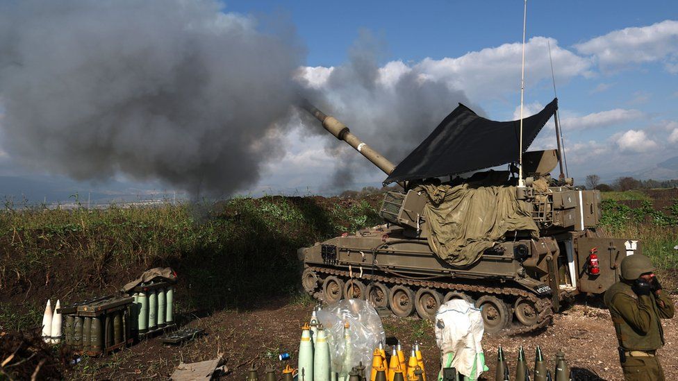 An Israeli soldier stands in front of a self-propelled artillery howitzer in northern Israel as it fires a shell towards southern Lebanon (4 January 2024)