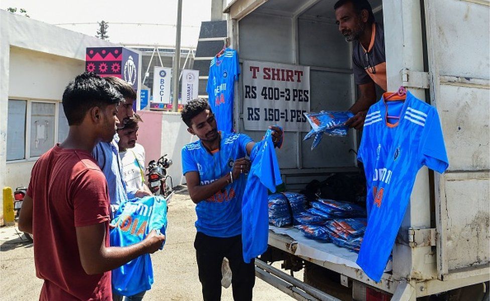 A vendor (C) sells Indian cricket jerseys to customers outside the Narendra Modi Stadium in Ahmedabad on October 10, 2023.