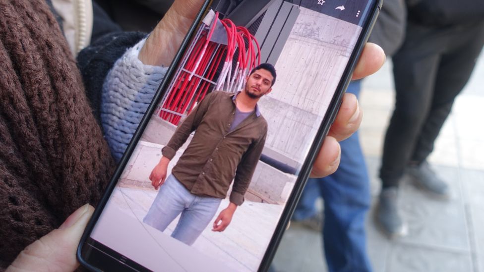 A person holds a phone showing a picture of a man