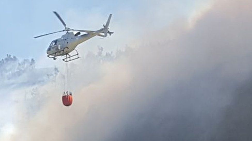 Helicopters carrying water to drop on fire