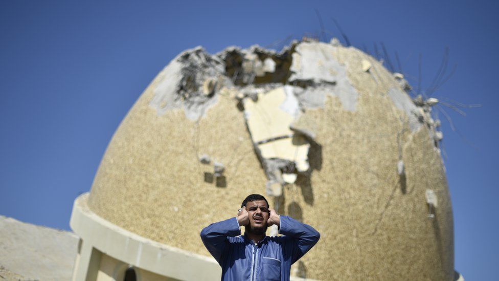 A Palestinian recites the Islamic call to prayer in the rubble of the Al-Amin Muhammad Mosque in Khan Younis
