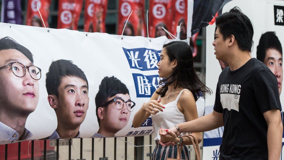 Pedestrians walk past a banner for new party Youngspiration showing disqualified candidate Edward Leung (L) and Baggio Leung (C) during the Legislative Council election in Hong Kong on September 4, 2016