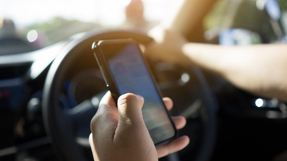 A close-up of a driver using a mobile in car