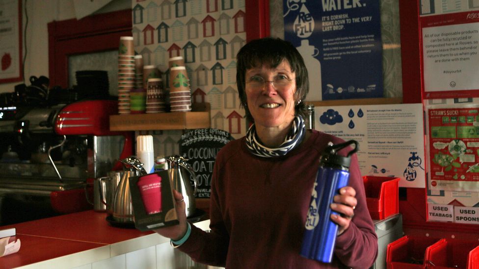 Deb Rosser holds a branded Refill Bude water bottle and coffee cup