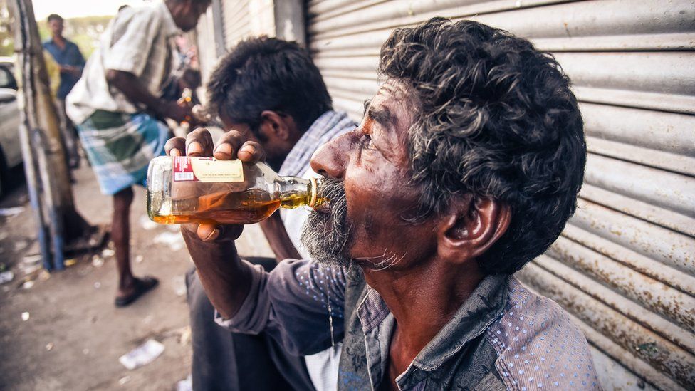 A man drinks outside an alcohol shop in Chennai