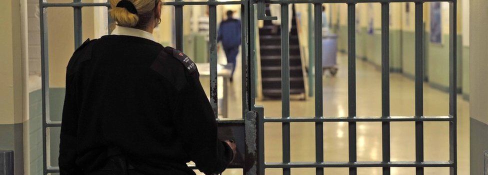 A prison officer locks a door
