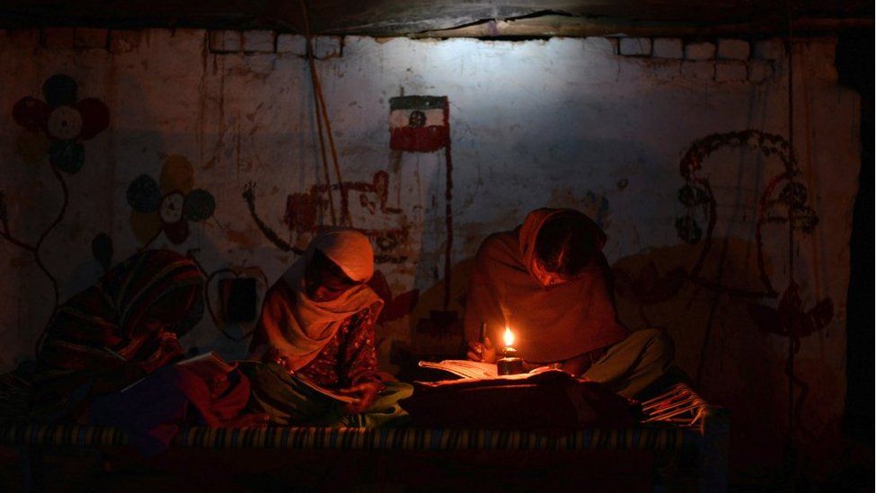 Two Indian girls study by candlelight