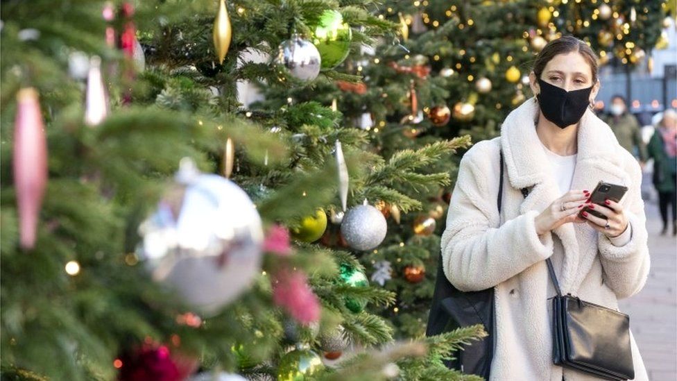 Woman in mask by Christmas tree