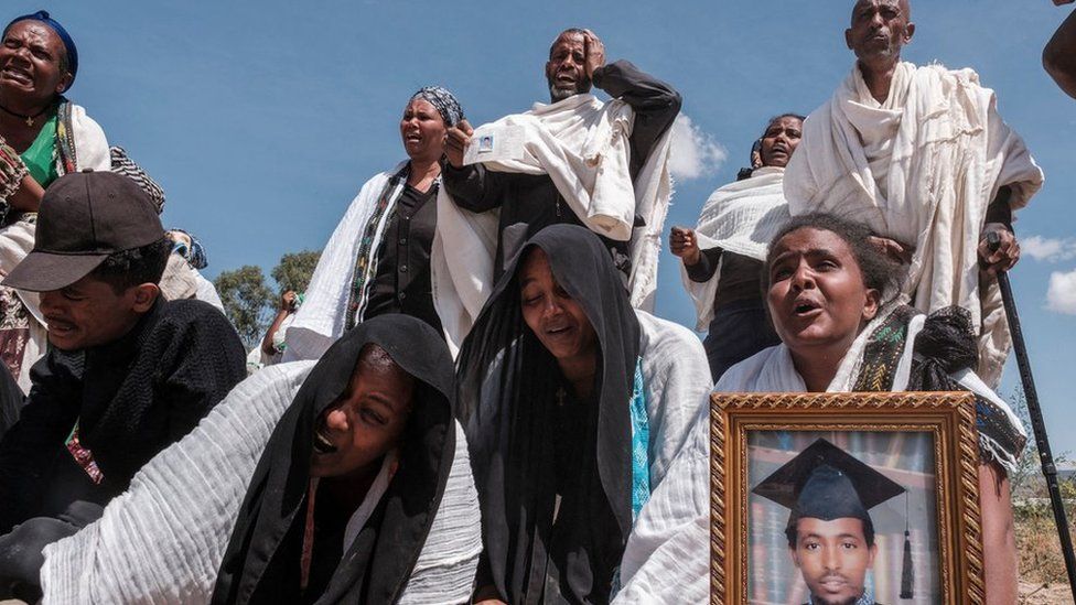 People react as they stand next to a mass grave containing the bodies of 81 victims of Eritrean and Ethiopian forces, killed during violence of the previous months, in the city of Wukro, north of Mekele, on February 28, 2021.