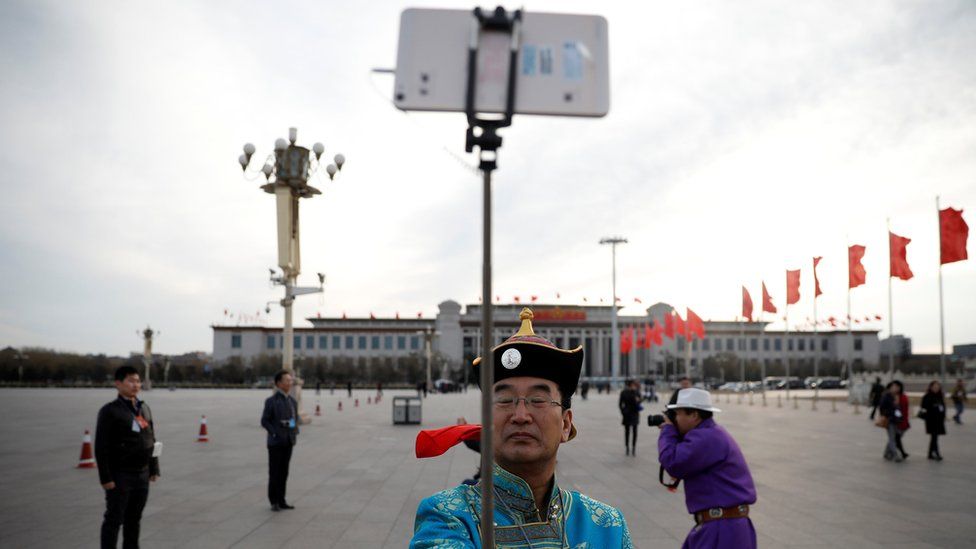 An ethnic minority man poses for a selfie on Tiananmen Square outside the Great Hall of the People ahead of the opening session of the National People's Congress in Beijing, 5 March
