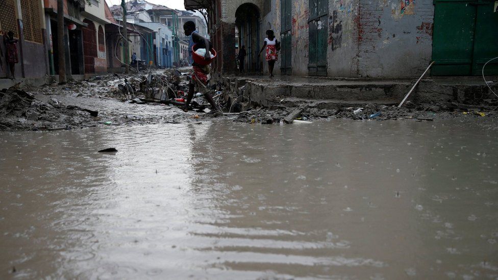 People walk in a flooded street after Hurricane Matthew hit Jeremie