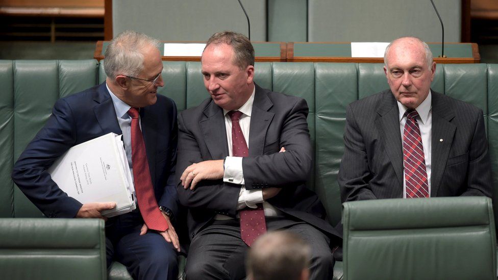 Australian Prime Minister Malcolm Turnbull (L) speaks to Australian Agriculture Minister Barnaby Joyce (C) as Federal Minister for Infrastructure and Regional Development Warren Truss sits next to them in the House of Representatives at Parliament House in Canberra, Australia, February 11, 2016
