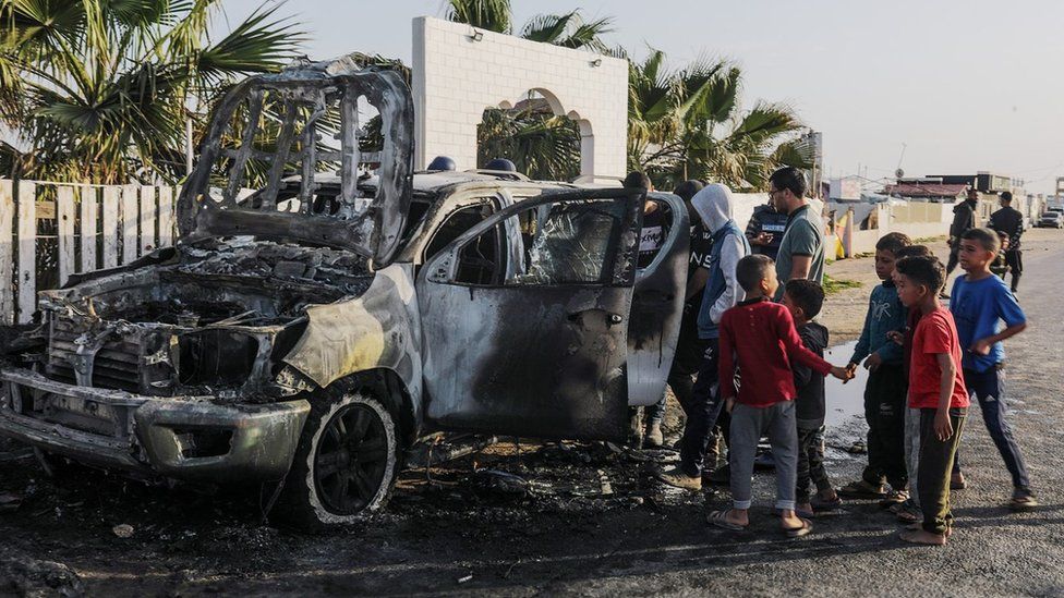 Palestinians inspect a World Central Kitchen vehicle that was destroyed in an Israeli air strike south of Deir al-Balah, in the Gaza Strip (2 April 2024)