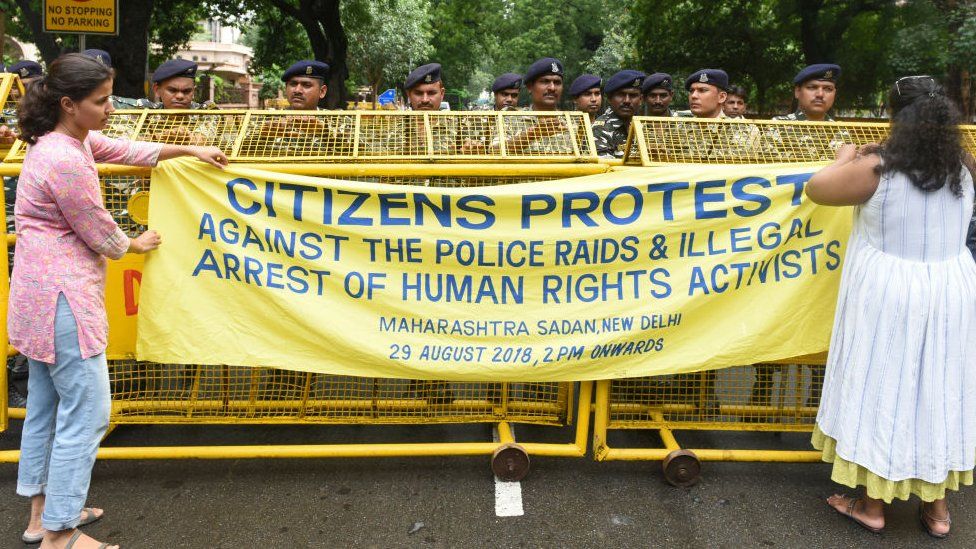 Delhi Police personnel stand on duty as people stage a protest against the arrest of five activists