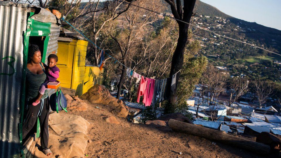 A women carries her child outside her shack at Imizamo Yethu settlement on May 17, 2018 in Hout Bay outside Cape Town, South Africa.
