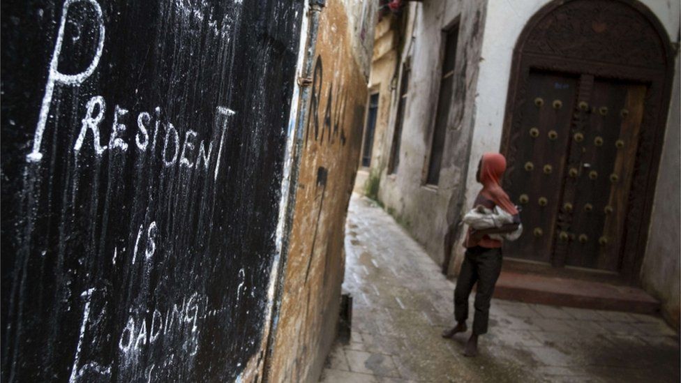 A young boy walks past graffiti that reads "president is loading" in historical Stone Town, on November 2, 2015