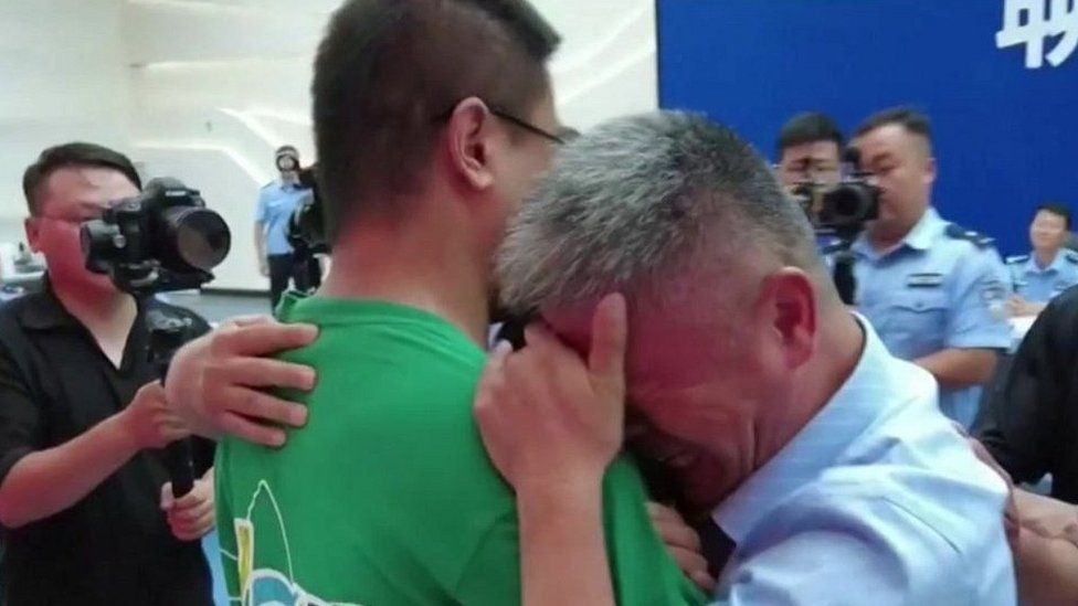 Го Гантан (справа) обнимает своего давно потерянного сына, который был похищен у него в Китае 24 года назад, 13 июля 2021 года