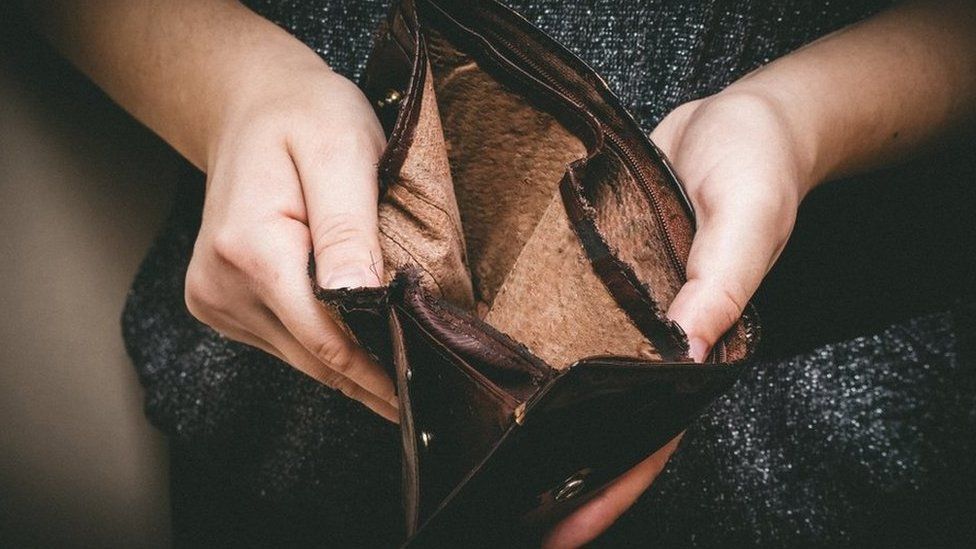 A woman holds an empty wallet in her hands