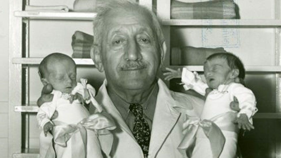 Martin Couney holding two babies