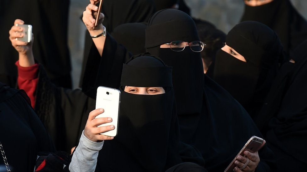 Women dressed in niqab holding phones