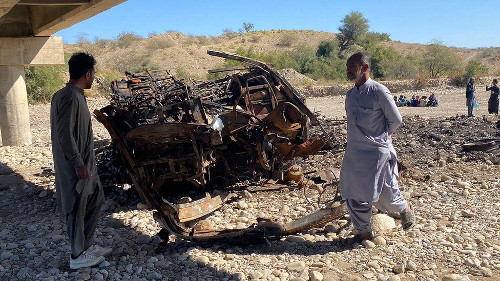 Residents look at the wreckage of a burnt passenger bus in Lasbela district of Pakistan's Balochistan province on 29 January