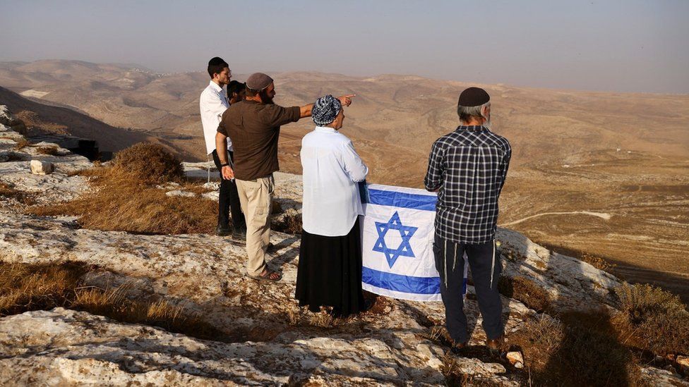 Даниэлла Вайс, ветеран-лидер поселенцев, держит израильский флаг во время разведывательной миссии по поиску новых вершин холмов для поселения недалеко от израильского поселения Кохав-Ха-Шахар на оккупированном Западном берегу (6 ноября 2022 г.)