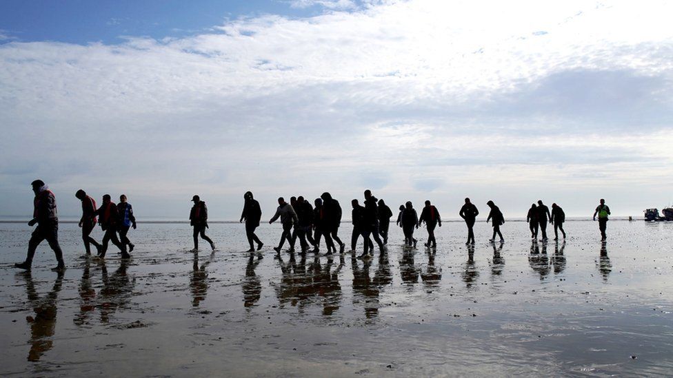 A group of people thought to be migrants walk up the beach after being brought in to Dungeness, Kent, onboard the RNLI Dungeness Lifeboat, following a small boat incident in the Channel. Picture date: Tuesday May 17, 2022