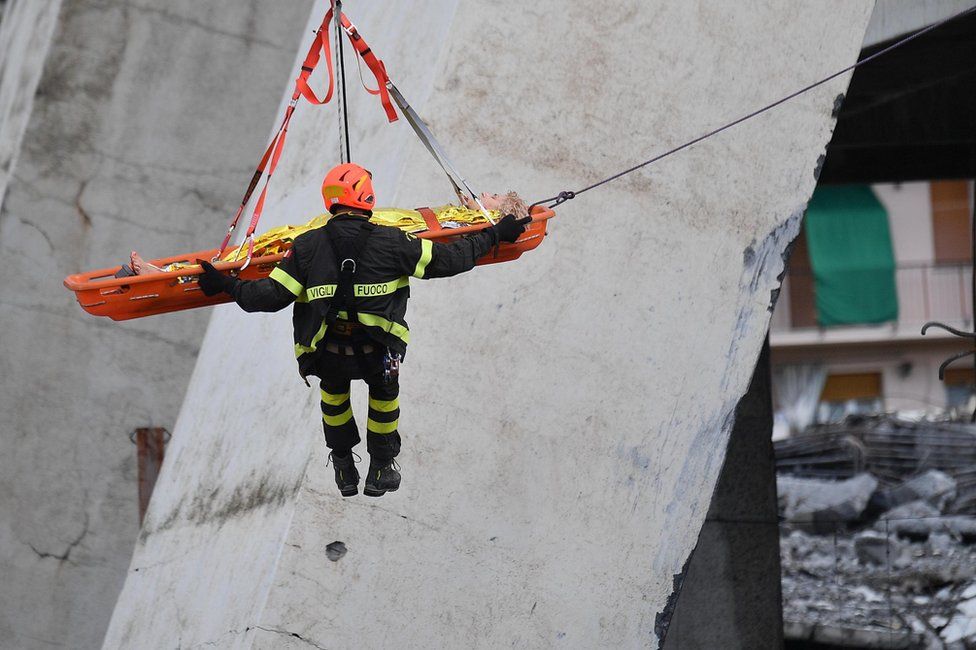 Rescuers recover an injured person after a highway bridge collapsed in Genoa, Italy, 14 August 2018