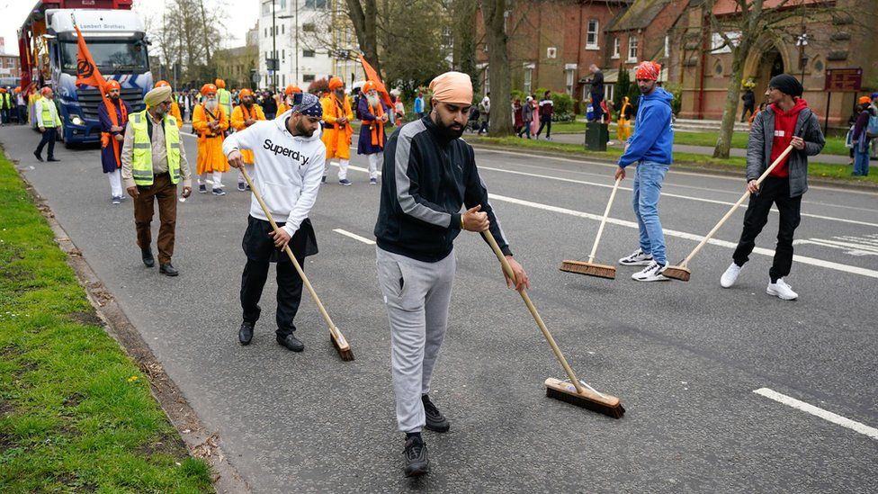 People sweep the road in front of the Panj Pyare as they take part in the Nagar Kirtan procession through the city centre in Southampton
