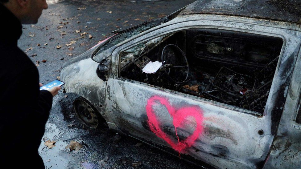 A man looks at a burned car in a street in Paris on December 2, 2018, a day after clashes during a protest of Yellow vests (Gilets jaunes) against rising oil prices and living costs.