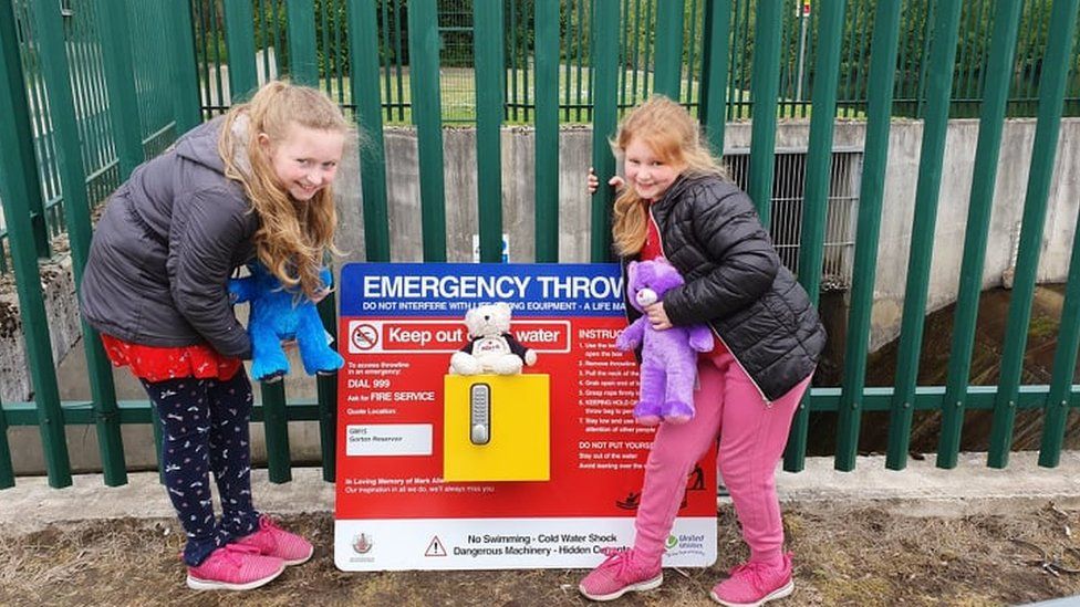 Mark's siblings Caitlin (left) and Meg as an emergency throwline station is installed next to the lake where Mark drowned