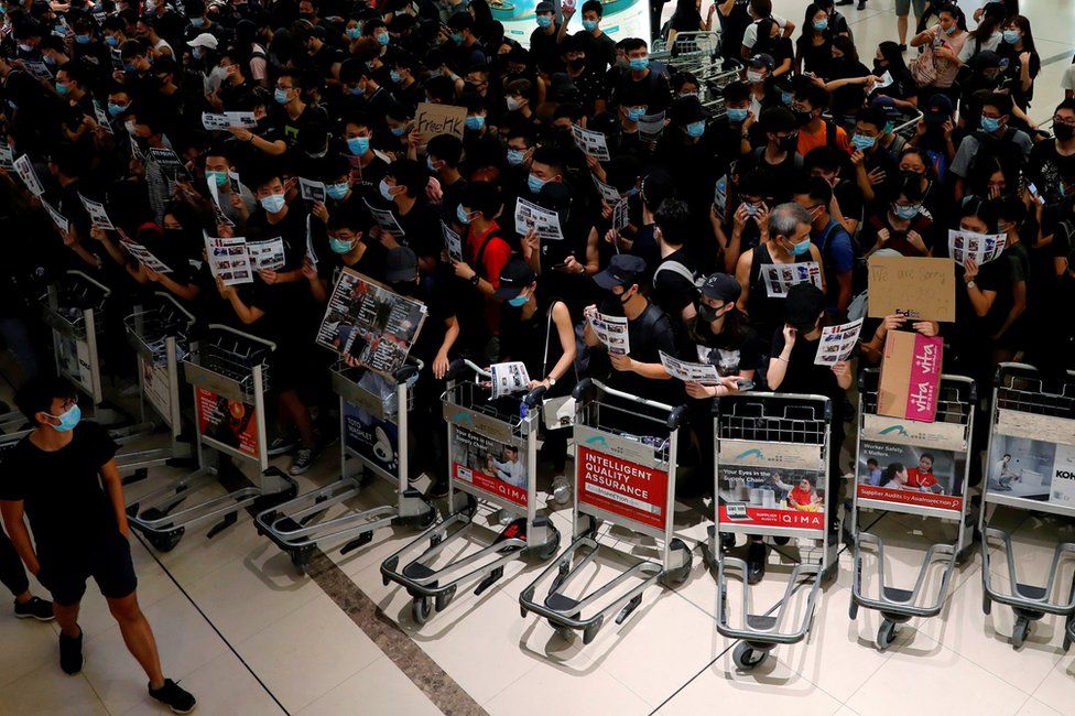 Anti-extradition bill protesters use trolleys to stop passengers from entering the security gates during a mass demonstration after a woman was shot in the eye, at the Hong Kong international airport, in Hong Kong China