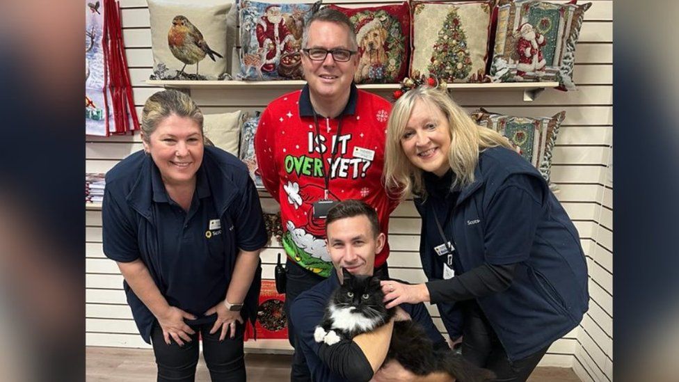 Staff posing with a cat in a garden centre