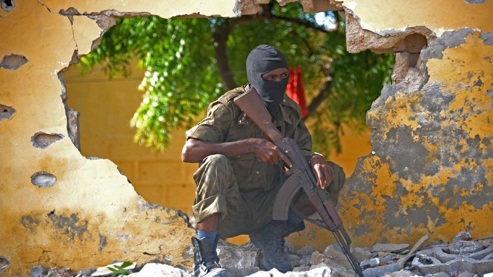 A Somali soldier stands guard next to the site where al-Shabab militants carried out a suicide attack in Mogadishu