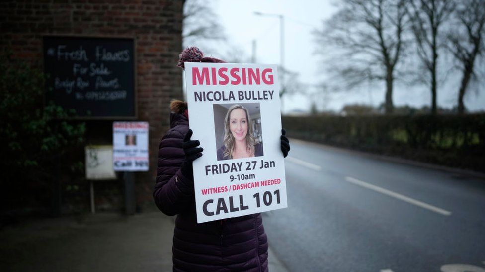 A woman holding up a poster appealing for information about Nicola Bulley's disappearance