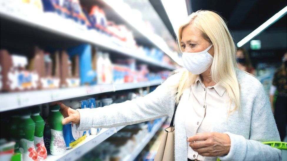 Woman in face mask in supermarket (stock image)