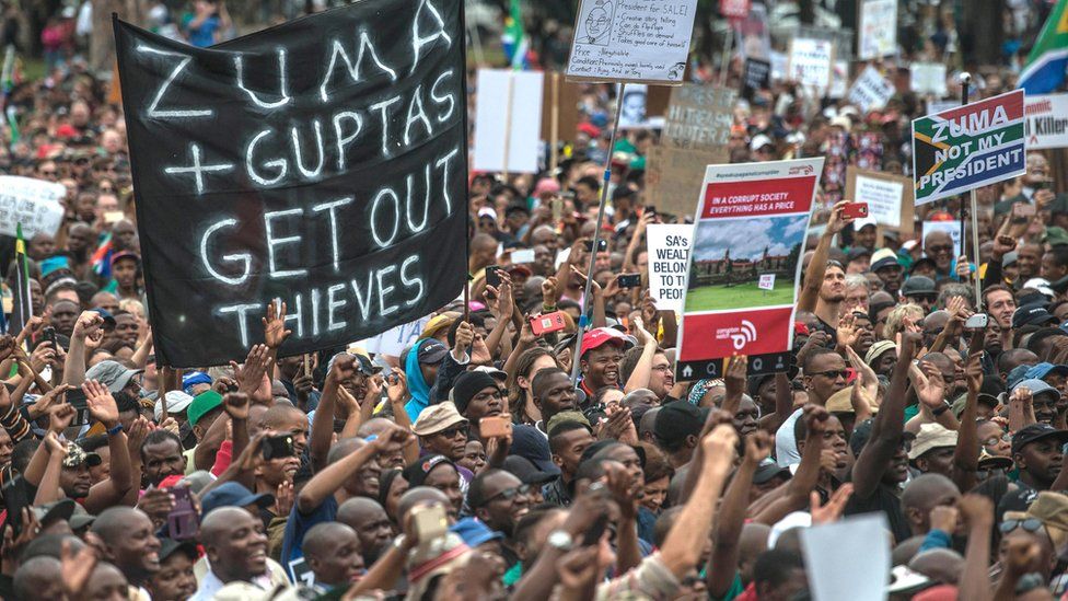 Protester hold banner saying "Zuma and Guptas Get Out Thieves"