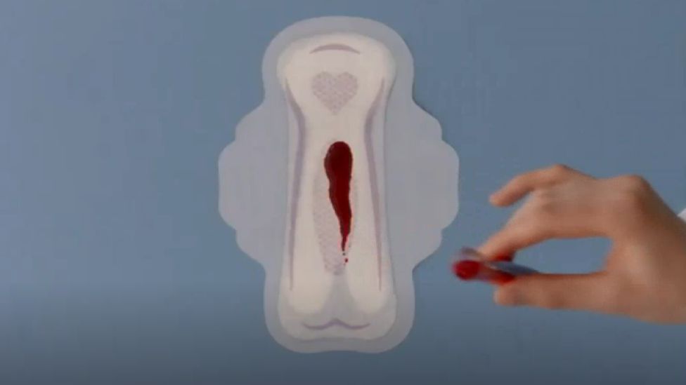 A sanitary pad with a streak of blood-like red liquid on it