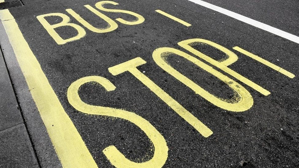 Bus stop sign with yellow paint on asphalt