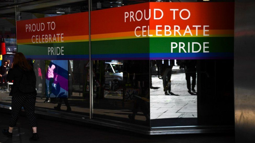 Shop with rainbow flag sticker in window and 'proud to celebrate pride' message