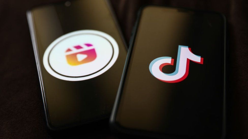 Смартфон с логотипом Instagram Reels рядом с другим смартфоном с логотипом TikTok