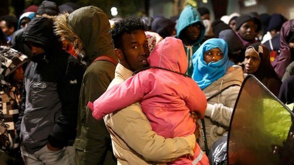 Migrants wait before entering buses
